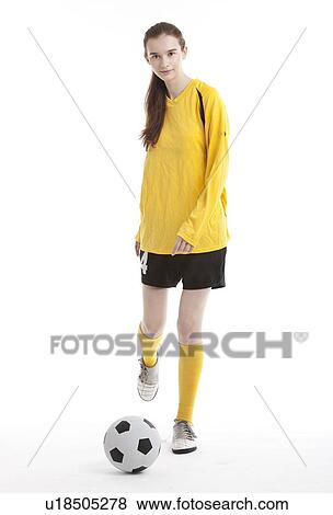 Stock Photo - Portrait of young female soccer player kicking the ball against white background. Fotosearch