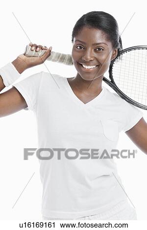 Stock Image - Portrait of young female tennis player holding racket over white background. Fotosearch