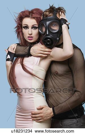 Portrait of young man in gas mask embracing funky woman over blue background View Large Photo Image Picture - Portrait of young man in gas mask embracing funky woman over blue background. Fotosearch