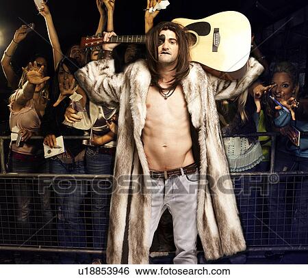 Stock Photograph - Portrait of young rock musician with guitar posing for excited audience at concert. Fotosearch