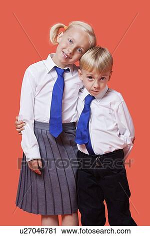 Portrait of young siblings in school uniform with arm around over orange background View Large Photo Image Stock Image - Portrait of young siblings in school uniform with arm around over orange background. Fotosearch