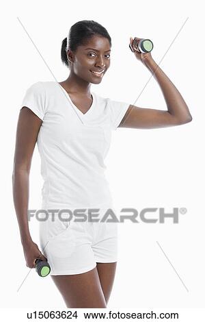 Picture - Portrait of young woman raising dumbbell over background. Fotosearch