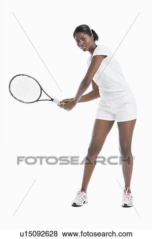Stock Photo - Portrait of young woman with tennis racket standing over white background. Fotosearch