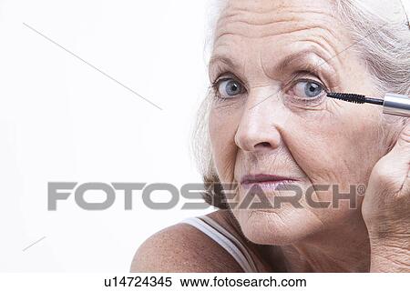 Stock Photography - Senior woman applying mascara. Fotosearch