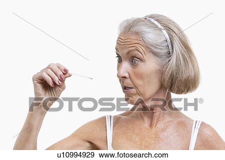 Senior woman checking thermometer against white background View Large Photo Image Stock Photo - Senior woman checking thermometer against white background. Fotosearch