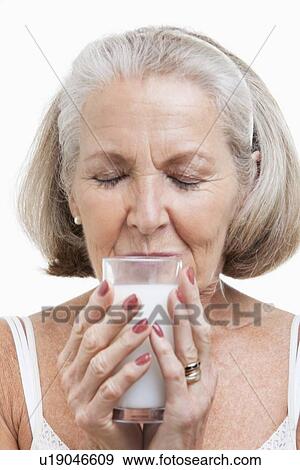 Stock Photo - Senior woman drinking milk against white background. Fotosearch