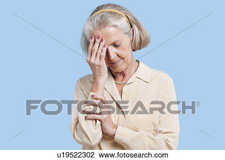 Senior woman suffering from headache against blue background View Large Photo Image Stock Image - Senior woman suffering from headache against blue background. Fotosearch