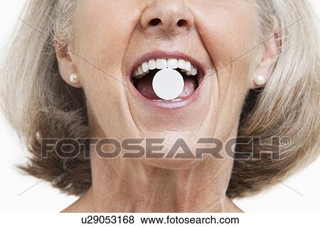 Senior woman with a pill between her teeth against white background View Large Photo Image Stock Photo - Senior woman with a pill between her teeth against white background. Fotosearch