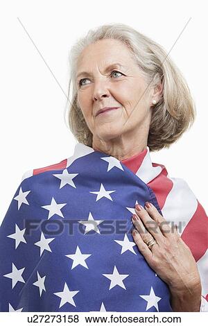 Senior woman wrapped in American flag against white background View Large Photo Image Stock Photo - Senior woman wrapped in American flag against white background. Fotosearch