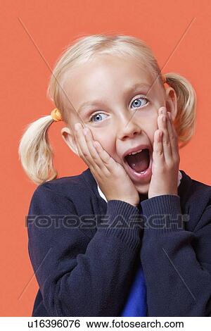 Surprised young schoolgirl with hands on face over orange background View Large Photo Image Stock Photograph - Surprised young schoolgirl with hands on face over orange background. Fotosearch