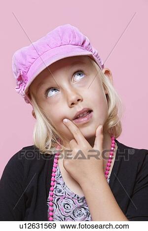Stock Photo - Thoughtful young girl wearing cap with finger on chin over pink background. Fotosearch