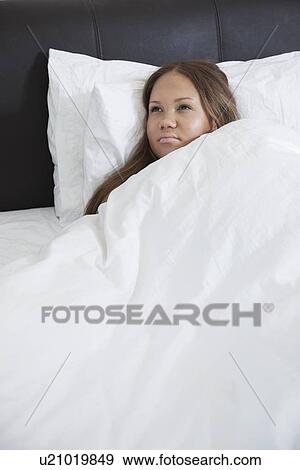 Thoughtful young pregnant woman lying in bed View Large Photo Image Stock Photo - Thoughtful young pregnant woman lying in bed. Fotosearch