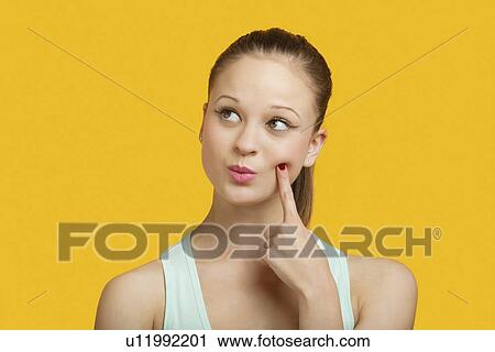 Thoughtful young woman looking sideways over yellow background View Large Photo Image Stock Image - Thoughtful young woman looking sideways over yellow background. Fotosearch