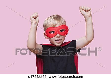 Young boy dressed in superhero costume with arms raised over pink background View Large Photo Image Stock Image - Young boy dressed in superhero costume with arms raised over pink background. Fotosearch