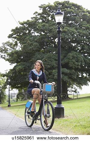Stock Image - Young businesswoman commuting by her bicycle. Fotosearch