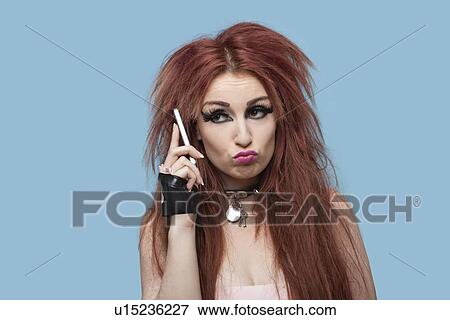 Young funky woman puckering while using cell phone over blue background View Large Photo Image Stock Photo - Young funky woman puckering while using cell phone over blue background. Fotosearch