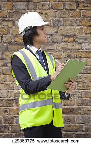Young male supervisor writing notes at construction site View Large Photo Image Stock Photography - Young male supervisor writing notes at construction site. Fotosearch