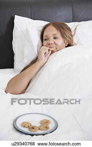 Young pregnant woman eating cookies in bed View Large Photo Image Stock Photo - Young pregnant woman eating cookies in bed. Fotosearch
