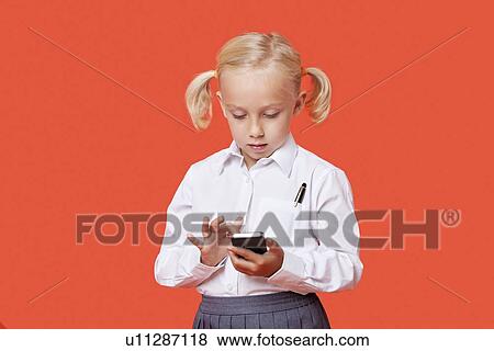 Stock Photo - Young school girl reading text messages over orange background. Fotosearch