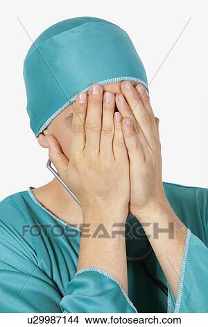 An upset male surgeon covering face with hands against gray background View Large Photo Image Picture - An upset male surgeon covering face with hands against gray background. Fotosearch