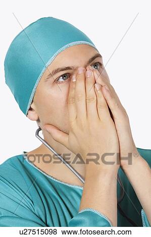 An upset male surgeon in scrubs looking up against white background View Large Photo Image Stock Photo - An upset male surgeon in scrubs looking up against white background. Fotosearch