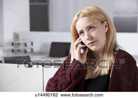Stock Image - Beautiful young businesswoman using cell phone at office. Fotosearch