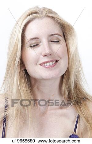 Stock Image - Beautiful young woman with eyes closed smiling against white background. Fotosearch