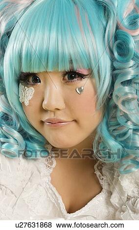 Stock Photo - Close-up portrait of young woman with blue hair dressed as a doll. Fotosearch