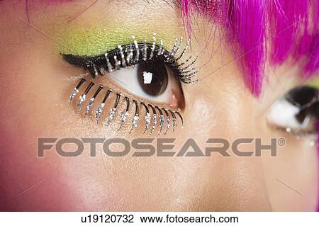 Stock Image - Extreme close-up of young funky woman's face with false eyelashes. Fotosearch