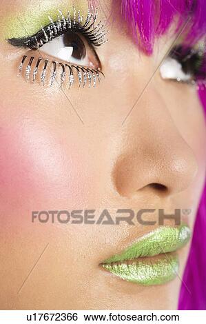 Stock Photograph - Extreme close-up of young funky woman's face with false eyelashes and green lipstick. Fotosearch