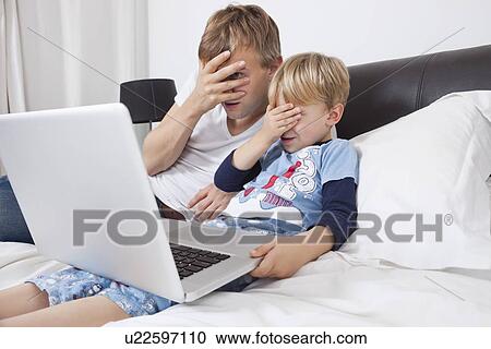 Father and son watching scary movie on laptop in bed View Large Photo Image Stock Image - Father and son watching scary movie on laptop in bed. Fotosearch