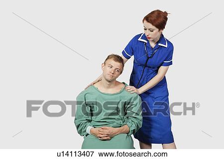 Female nurse consoling male patient against gray background View Large Photo Image Stock Photo - Female nurse consoling male patient against gray background. Fotosearch