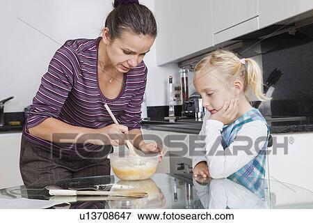 Girl looking at mother cooking in kitchen View Large Photo Image Stock Photo - Girl looking at mother cooking in kitchen. Fotosearch