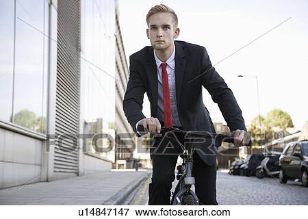 Handsome young businessman riding bicycle on street View Large Photo Image Stock Photo - Handsome young businessman riding bicycle on street. Fotosearch