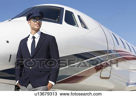 Handsome young pilot standing by private airplane View Large Photo Image Stock Image - Handsome young pilot standing by private airplane. Fotosearch