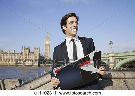 Happy young businessman with book standing against Big Ben clock tower, London, UK View Large Photo Image Stock Image - Happy young businessman with book standing against Big Ben clock tower, London, UK. Fotosearch
