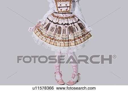 Low section of young woman in doll outfit standing over gray background View Large Photo Image Stock Photograph - Low section of young woman in doll outfit standing over gray background. Fotosearch