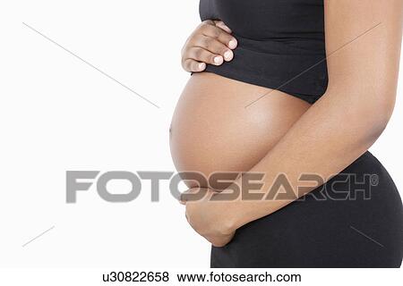 Mid section of young pregnant woman with hands on stomach over white background View Large Photo Image Stock Photo - Mid section of young pregnant woman with hands on stomach over white background. Fotosearch