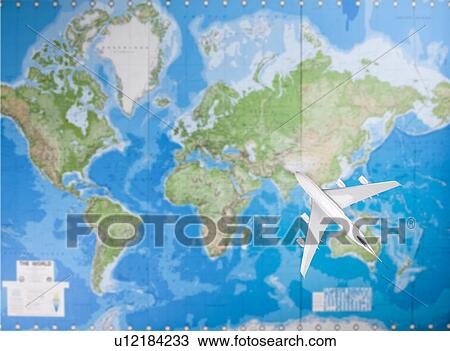 Stock Image - Model airplane flying over world map. Fotosearch