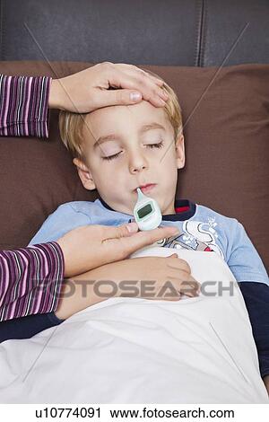 Mother checking unwell little boy's temperature with thermometer View Large Photo Image Stock Image - Mother checking unwell little boy's temperature with thermometer. Fotosearch