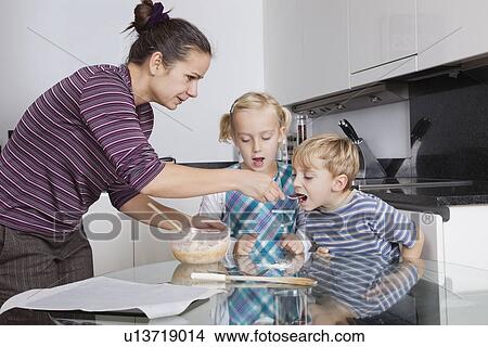 Mother with children baking and tasting cookie batter in kitchen View Large Photo Image Picture - Mother with children baking and tasting cookie batter in kitchen. Fotosearch