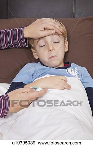 Stock Photo - Mother with thermometer checking little boy's temperature. Fotosearch