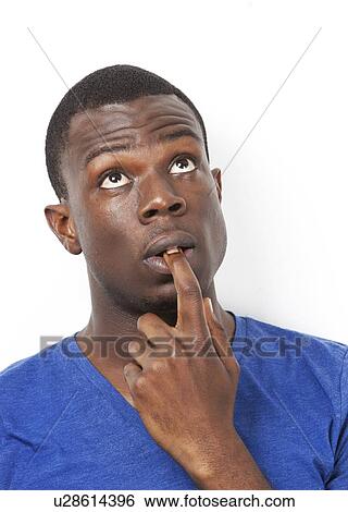 Pensive young African American man with finger in mouth against white background View Large Photo Image Stock Photograph - Pensive young African American man with finger in mouth against white background. Fotosearch
