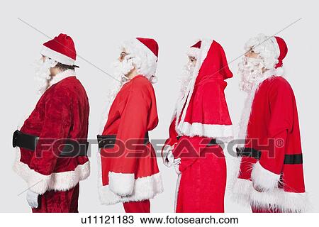 Stock Image - People in Santa costume standing in row against gray background. Fotosearch