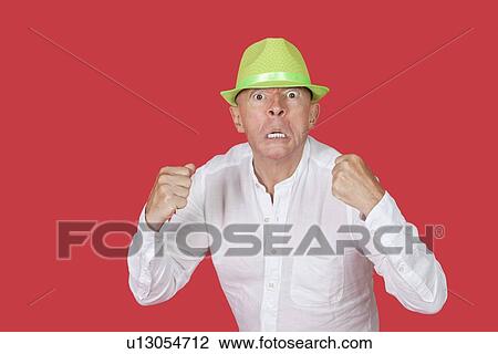 Portrait of an angry senior man clenching fists against red background View Large Photo Image Stock Image - Portrait of an angry senior man clenching fists against red background. Fotosearch