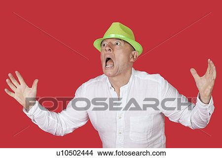 Picture - Portrait of an shocked man screaming against red background. Fotosearch
