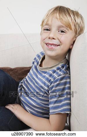 Stock Image - Portrait of cute boy relaxing on sofa. Fotosearch
