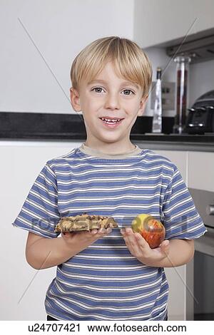 Portrait of cute little boy choosing between apple and chocolate chip cookie View Large Photo Image Stock Image - Portrait of cute little boy choosing between apple and chocolate chip cookie. Fotosearch