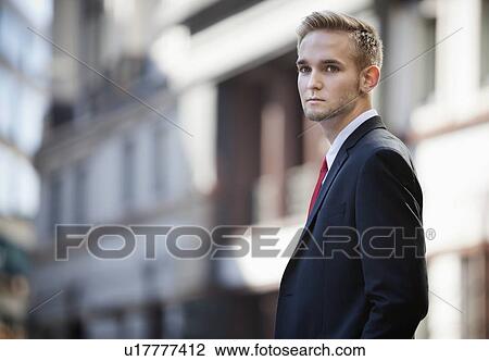 Portrait of handsome businessman in suit standing against building View Large Photo Image Stock Image - Portrait of handsome businessman in suit standing against building. Fotosearch
