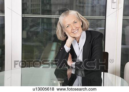 Portrait of happy senior businesswoman sitting at table View Large Photo Image Stock Photo - Portrait of happy senior businesswoman sitting at table. Fotosearch